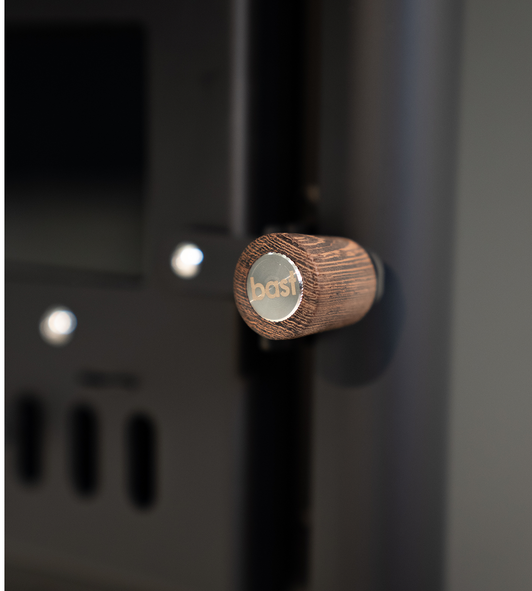 Wooden knob with 'BAST' branding on a wood-fired stove for a outdoor sauna tent.