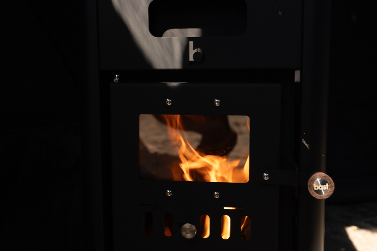 Lighting the wood-fired stove inside a BAST sauna tent
