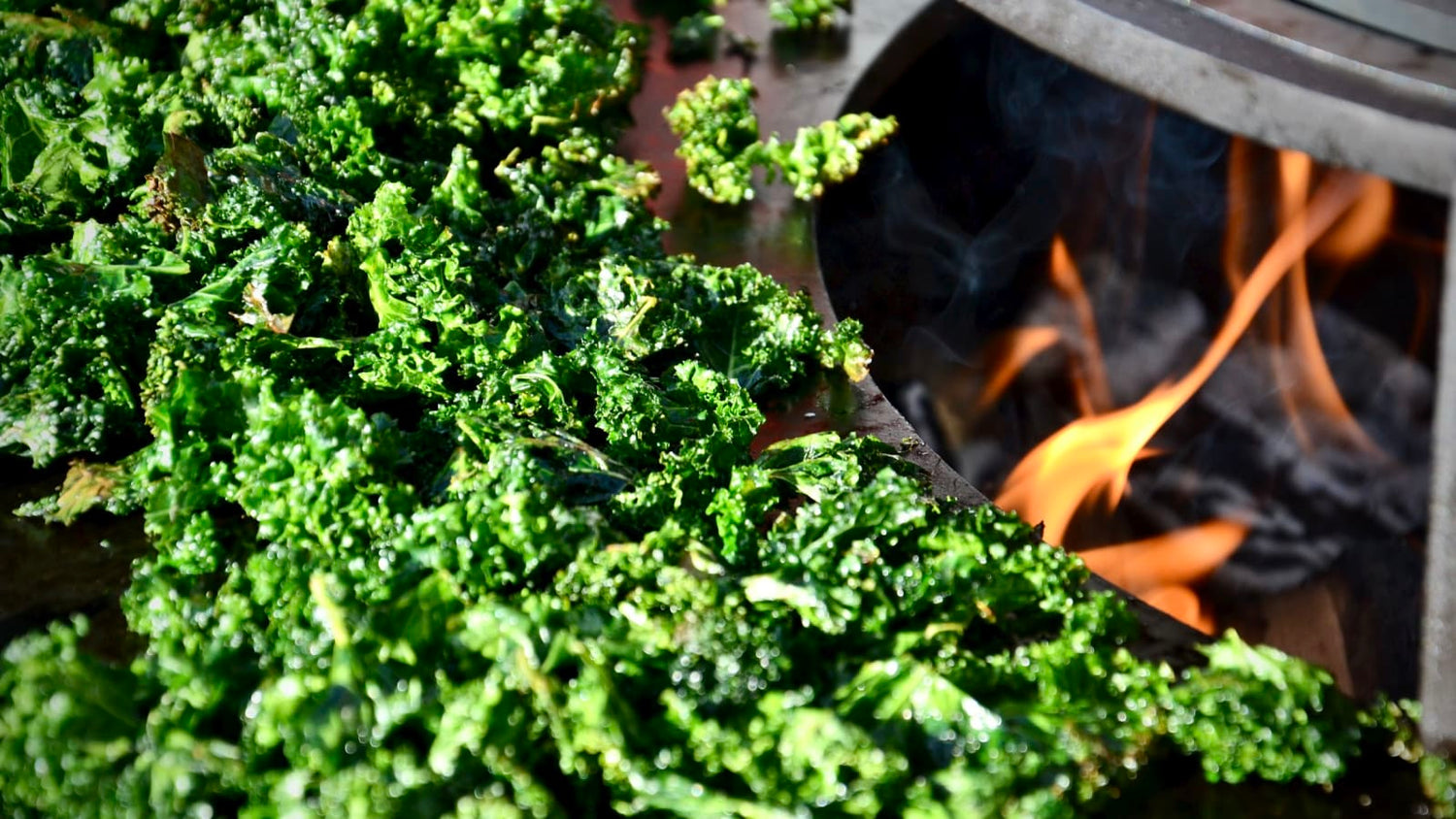 Crispy kale chips roasting on the OFYR grill plate over the autumn fire – a seasonal snack and perfect apéro treat with a smoky touch.