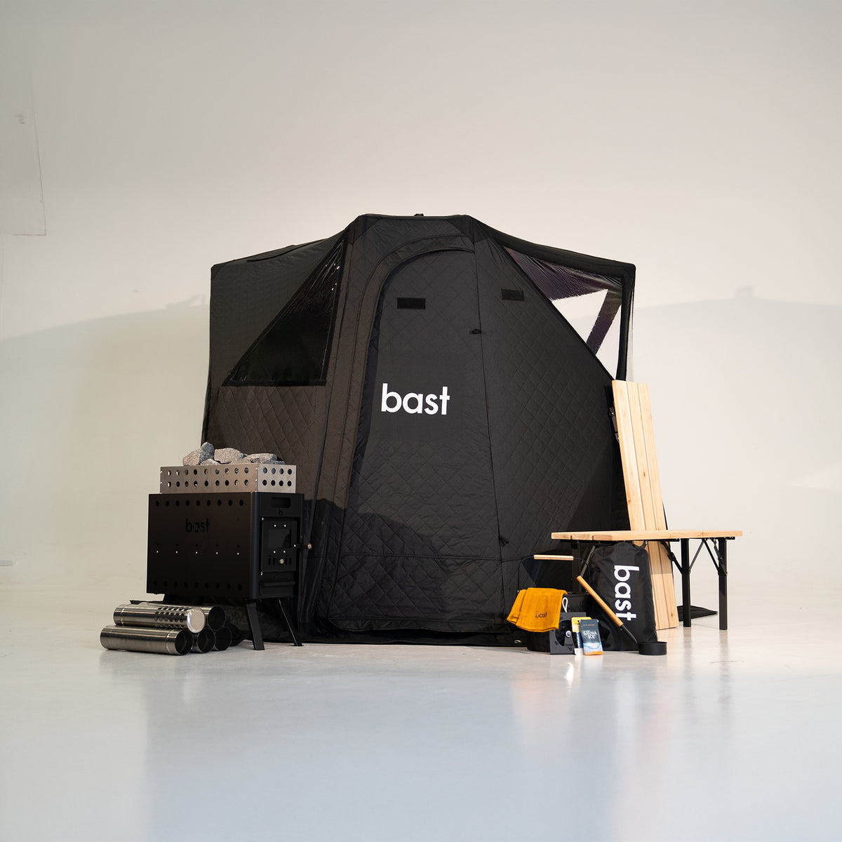 Black pop-up sauna tent kit for 2-4 people showing tent, stove, and accessories included in the premium kit.