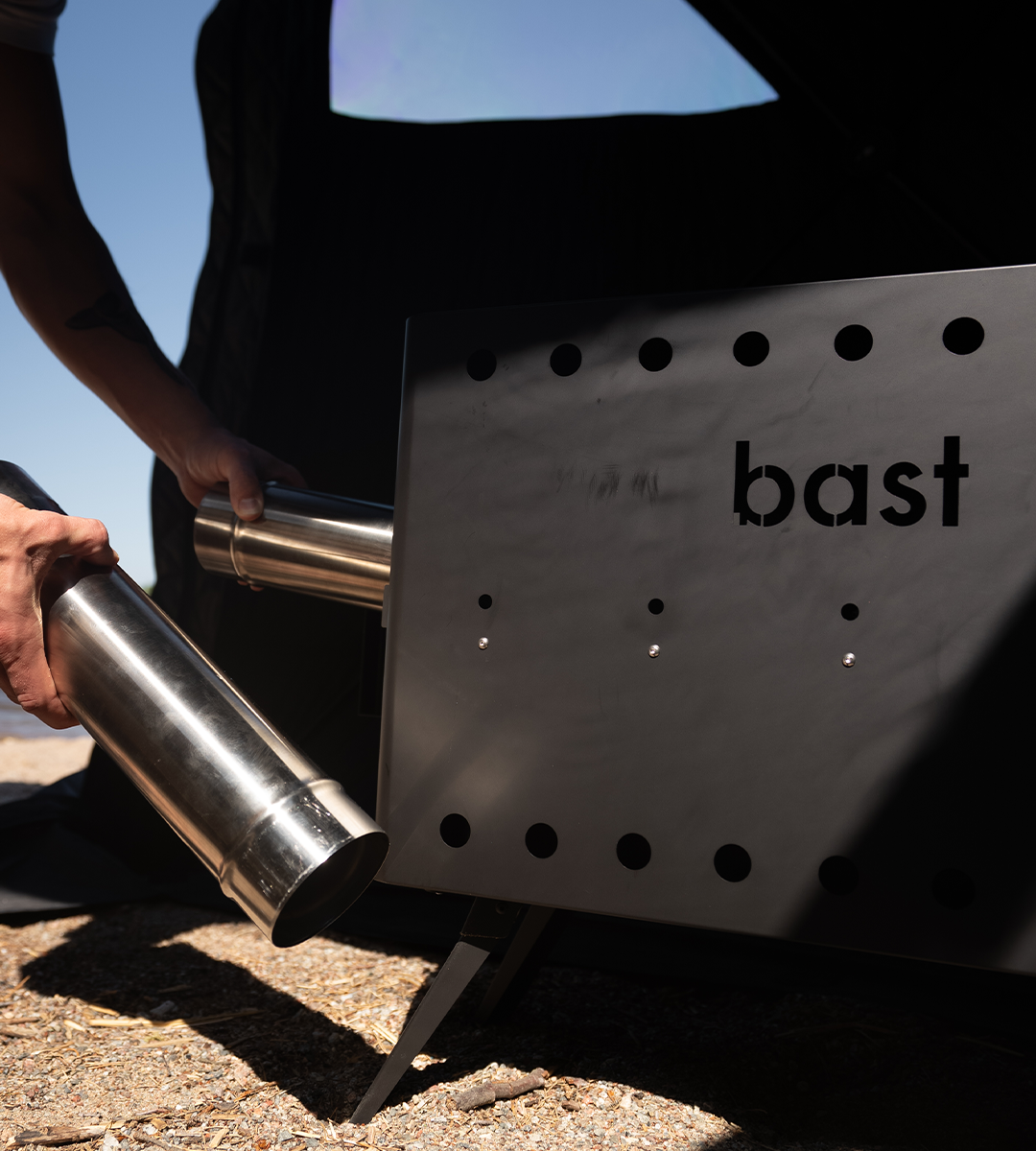 Adding pipes to assemble the BAST wood-fired stove for an outddor sauna tent. 
