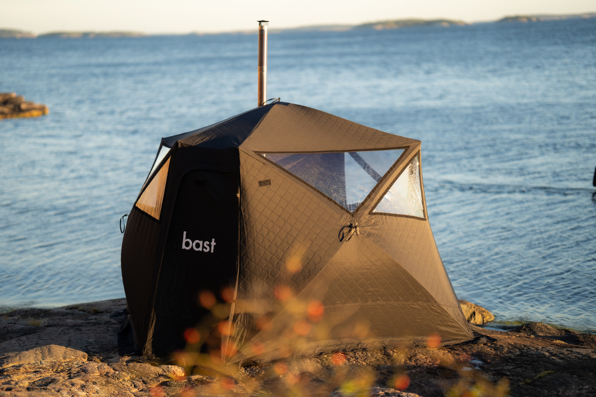 Mobile sauna tent set up beside a lake for an outdoor sauna experience